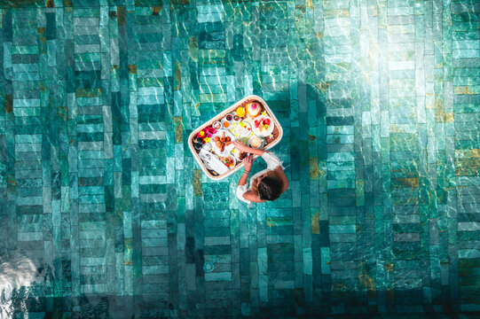 Aerial view of a woman having a floating breakfast in a swimming pool of a luxury resort, Ilot Lievres, Trou d'Eau Douce, Flacq district, Mauritius.