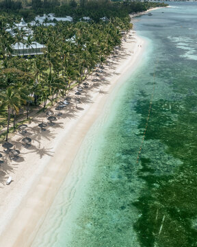 Aerial view of Flic En Flac beach, a tropical oasis and travel destination with umbrellas on the shoreline in Riviere Noire, Mauritius.
