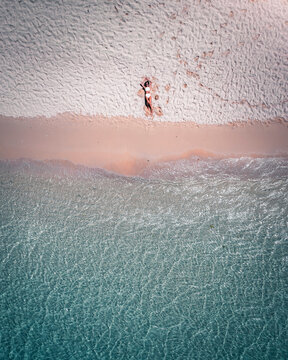 Aerial view of a woman relaxing on Pomponette Public beach along the shoreline, Chemin Grenier, Savanne District, Mauritius.