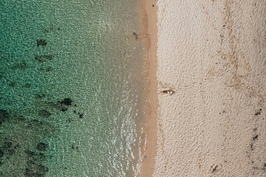 Aerial view of a woman relaxing on Pomponette Public beach along the shoreline, Chemin Grenier, Savanne District, Mauritius.