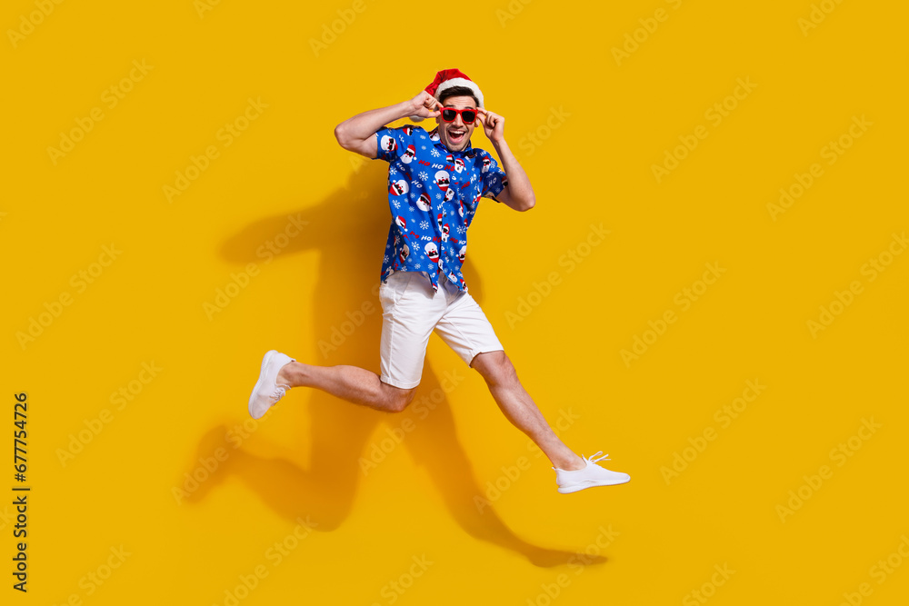 Poster Full length profile photo of cheerful overjoyed person jumping arms touch sunglass isolated on yellow color background