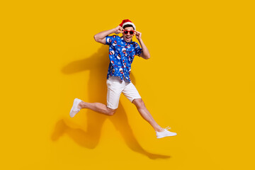 Fototapeta na wymiar Full length profile photo of cheerful overjoyed person jumping arms touch sunglass isolated on yellow color background