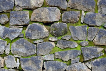 Closeup shot of a stacked stone wall with green moss