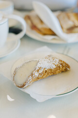 Sweet cannoli stuffed with cream for breakfast on a table in a cafe.