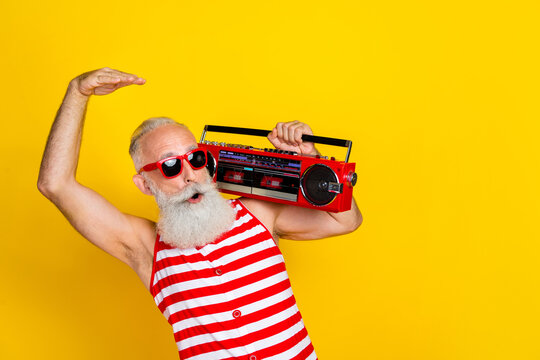 Photo of funny grandfather dancing boogie woogie party hold boombox looking copyspace with boombox isolated on yellow color background