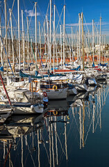 A jumble of small sailboats masts and lines against the sky and also reflected in the water, Barcelona Marina, Spain