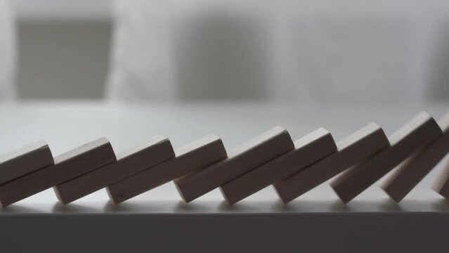 falling line of wooden domino blocks each knocking the next over, domino effect slow motion