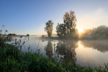River bank on an autumn morning in fog and frost.