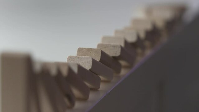 falling line of wooden domino blocks each knocking the next over, domino effect slow motion