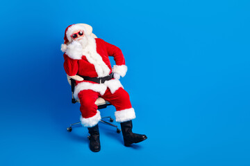 Full body photo of retired old man sit listen interested armchair wear trendy santa claus costume coat isolated on blue color background