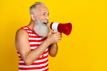 Photo of elderly strong pensioner in red striped swimsuit scream bullhorn at the beach for tourists isolated on yellow color background