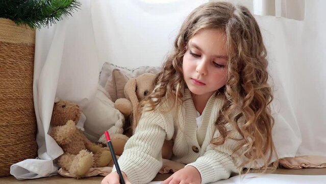 A child draws a picture on paper with a pencil, a holiday concept