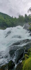 Vertical closeup of foamy water of a river flowing in a forest