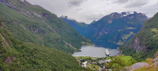 Drone shot of a lake with a ship of its surface surrounded by green-covered hills