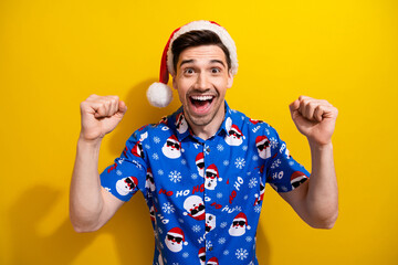 Photo of funky young student guy prepare new year holiday fists up hooray astonished santa claus gifts isolated on yellow color background