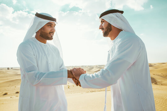 Two business men wearing traditional uae white kandura spending time in the desert of Dubai