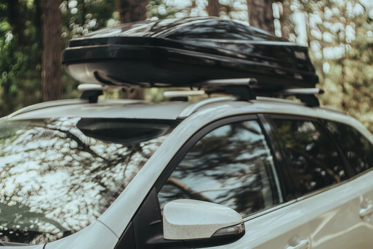 Defocused image of a car with an attached roofbox (roof box) on it. Tinted photo taken with a vintage lens. The mood of  journey, summer vacation, road tripping. New experiences and adventures.