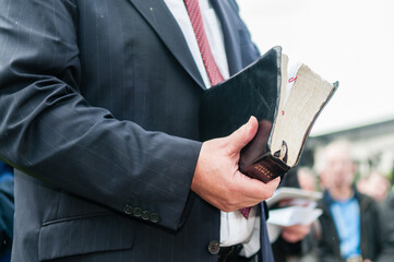 Minister holding a large, well used bible