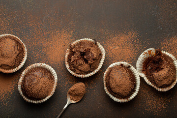 Chocolate browny muffins and cocoa in teaspoon top view on brown rustic stone background, sweet...