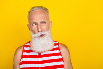 Photo of suspicious unsure senior man wear red striped swimsuit looking empty space isolated yellow color background
