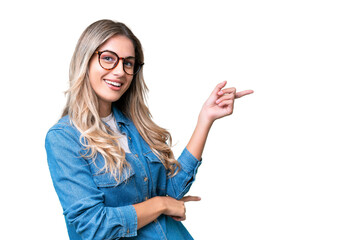 Young Uruguayan woman over isolated background pointing finger to the side