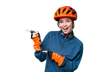 Young cyclist woman over isolated chroma key background surprised and pointing side