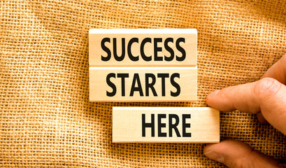 Success starts here symbol. Concept word Success starts here on beautiful wooden block. Businessman hand. Beautiful canvas background. Business motivational success starts here concept. Copy space.