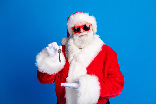 Photo portrait of retired old man hold point door key service dressed stylish santa claus costume coat isolated on blue color background