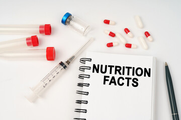 On the table are pills, injections, a syringe and a notepad with the inscription - nutrition facts