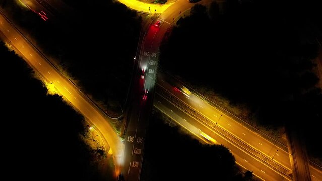 Aerial time lapse of night traffic, cars driving on highway roads under street lights