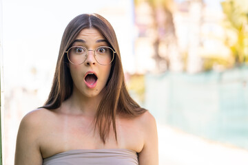 Young pretty Brazilian woman at outdoors With glasses and surprised expression