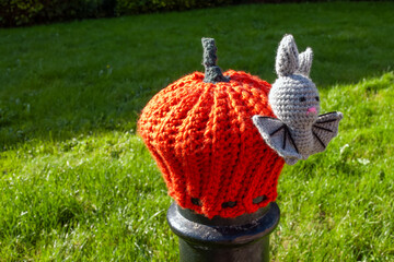 knitted bright orange pumpkin and bat bollard topper in Titchfield Hampshire England for Halloween - obrazy, fototapety, plakaty