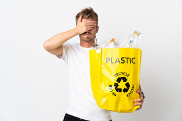 Young blonde man holding a recycling bag full of paper to recycle isolated on white background...