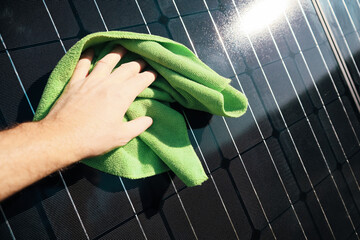Cleaning solar panel with wipe. Hand wipes solar panels from dirt. Solar panel or photovoltaic module maintenance. Selective focus