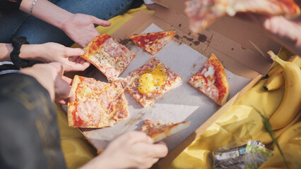 Young students' hands reach for the pizza.