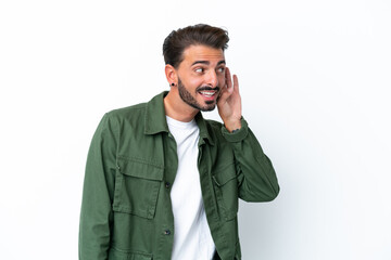 Young caucasian man isolated on white background listening to something by putting hand on the ear