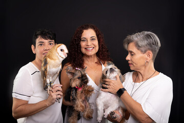 Three happy, confident lesbian women with their pets. An owl and Yorkshire and Shih Tzu dogs.