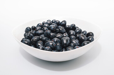 Bunches of blue grapes in white plate on white background. Berries, summer harvest, healthy eating