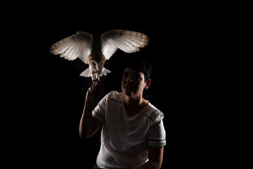 Studio shot of a beautiful baby owl with its wings outstretched and held by a woman. Wild animal.
