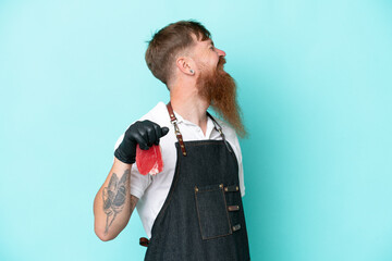 Butcher man wearing an apron and serving fresh cut meat isolated on blue background laughing in lateral position