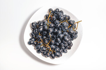 Bunches of blue grapes on a white plate. Healthy eating, winemaking, summer harvest, vineyard