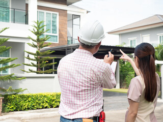 Owner and engineer are inspecting a new house at front yard. Checklist a new house. - obrazy, fototapety, plakaty
