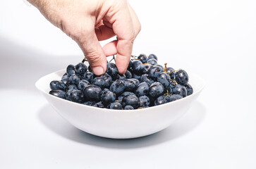 Bunches of blue grapes in white plate on white background. Berries, summer harvest, healthy eating