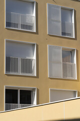Ivry-Sur-Seine, France - 09 27 2021: View of a graphic yellow facade of a building and windows and balcony behind with its shadow.