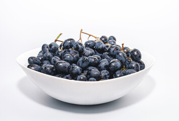Bunches of blue grapes on a white plate. Healthy eating, winemaking, summer harvest, vineyard