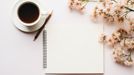 a cup of coffee and a notepad on a white surface with flowers and a pen on top of it.