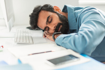 Exhausted indian man asleep at his desk
