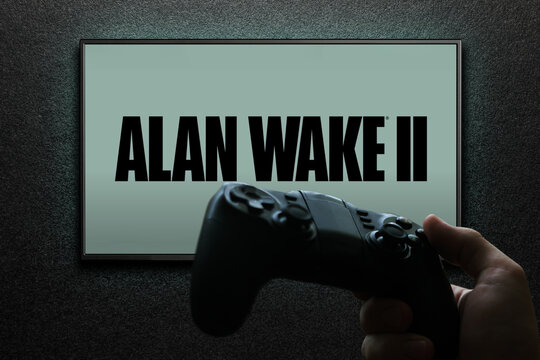 Alan Wake 2 game on TV screen with gamepad in hand on black textured wall with light. Astana, Kazakhstan - November 13, 2023.