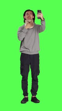 Front view of guy having cervical neck brace makes phone call informing family about his vertebral fracture injury. Full body greenscreen of wounded man wearing medical foam collar, speaking on