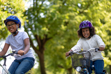 Fototapeta na wymiar Cute african american kids riding bikes in the park
